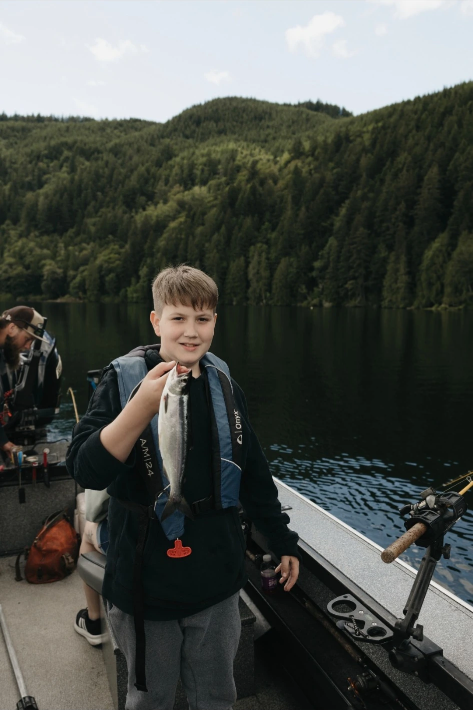 Youth learning to fish alongside an experienced guide on the lake